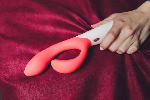 Woman in bedroom holding vibrator in hand